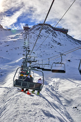 Fototapeta na wymiar Skiers on the skilift, skiers on slope in ski resort Italian Alps in sunny day on glacier Val Senales, Italy