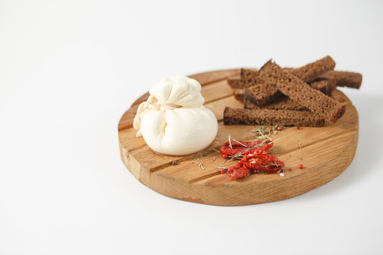 Italian, Buratto cheese with sun-dried tomatoes on a wooden Board with spices and bread