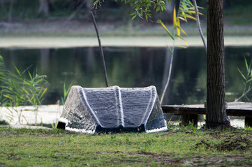 A boat waiting to sail. Renovated bottom of the boat looking at the sky. The bow of the boat is securely tied to a tree. The water of the lake in the background operates tempting.