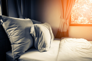 Bed maid-up with clean white pillows and bed sheets in beauty room. Close-up. Lens flair in sunlight.