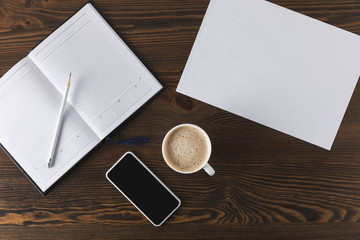 flat lay with smartphone, notebook, pencil and cup of coffee on wooden tabletop