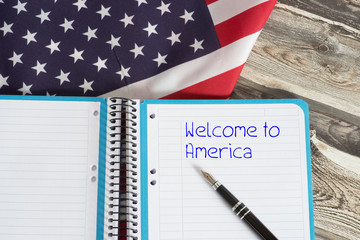 Amerikanische Flagge und ein Heft mit dem Slogan Willkommen in Amerika