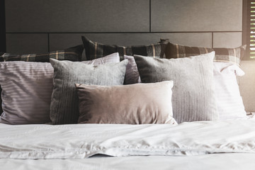 Bed maid-up with clean white pillows and bed sheets in beauty room. Close-up. Lens flair in sunlight.