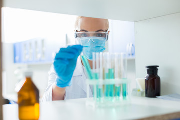Fototapeta premium Serious scientific researcher looking at the test tubes