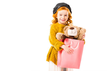 red hair child holding teddy bear in shopping bag isolated on white