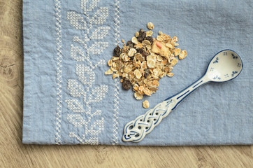 Obraz na płótnie Canvas Muesli and spoon with a blue pattern on the background of a blue tablecloth with embroidery on a wooden background