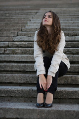 Young beautiful woman wearing beige jacket sitting on concrete s