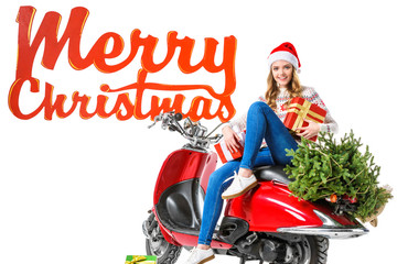 happy woman in santa hat sitting on red scooter with presents and christmas tree, isolated on white with Merry Christmas sign