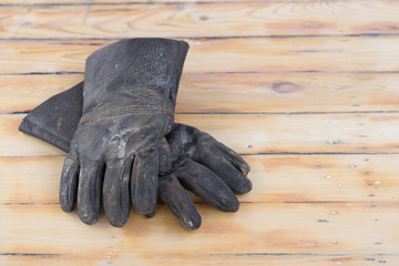 Black leather gloves are used on wooden background
