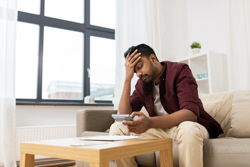 upset man with papers and calculator at home