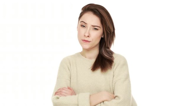 Portrait of serious young woman posing at camera with crossed arms feeling negative answering NO with shaking head expressing suspicion over white background closeup. Concept of emotions