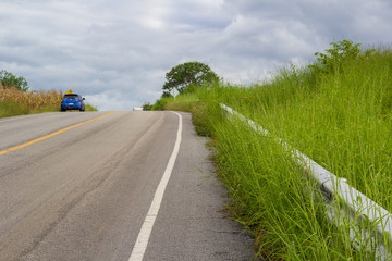 a car on rural asphalt road ahead to the mountain