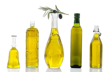 various olive oil glass jar, with branch of leaves and black berries on top of one on white backgound