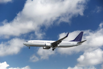Commercial passenger airplane landing or taking off from the airport with blue cloudy sky in the background