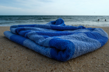 Fototapeta na wymiar Blue towel on sandy beach. Concept of having good vacation in warm tropical country