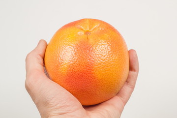 Grapefruit in hand on white background