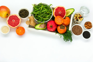 Healthy food in wooden tray: fruits, vegetables, seeds and greens on white background. Flat lay. Top view