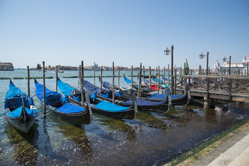 Fototapeta na wymiar Gondolas moored by Saint Mark square with San Giorgio di Maggiore church in Venice, Italy - June 20, 2017