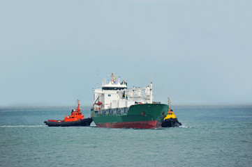 Tugboat assisting refrigerated cargo carrier
