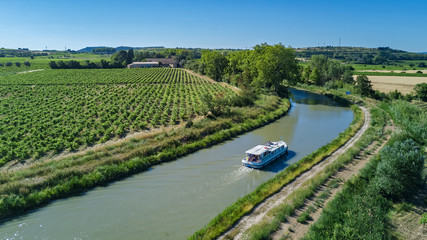 Aerial top view of boat in Canal du Midi from above, family travel by barge and vacation in Southern France
