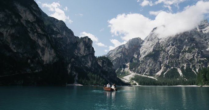 Just amazing landscape with big mountains with big lake and a romantic couple in the middle of lake with a wooden boat. 4k