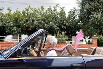 old woman driving a convertible car