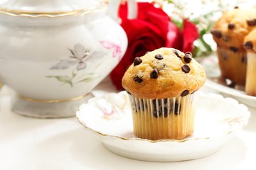Chocolate chip muffin with red rose  and coffee pot, selective focus