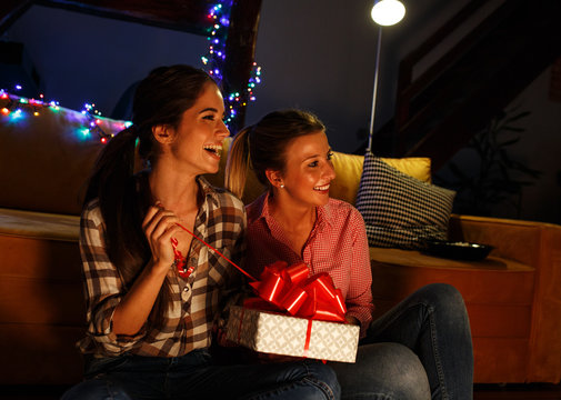 Young woman opens a gift which she got from her friend.Celebration concept.