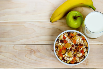 Healthy eating. On the wooden board are muesli, honey in a jar, a banana, an orange, a glass of milk.