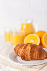 Freshly baked croissant, orange juice, fresh fruits, jam on white wooden background. French breakfast. Fresh pastries for morning. Delicious dessert. Closeup photography. Vertical banner