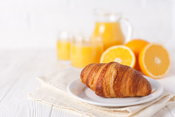 Freshly baked croissant, orange juice, fresh fruits, jam on white wooden background. French breakfast. Fresh pastries for morning. Delicious dessert. Closeup photography. Horizontal banner