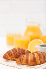 Freshly baked croissant, orange juice, fresh fruits, cup of coffee on white wooden background. French breakfast. Fresh pastries for morning. Delicious dessert. Closeup photography. Vertical banner