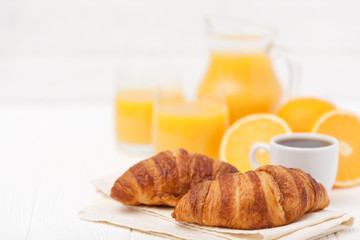 Freshly baked croissant, orange juice, fresh fruits, cup of coffee on white wooden background. French breakfast. Fresh pastries for morning. Delicious dessert. Closeup photography. Horizontal banner