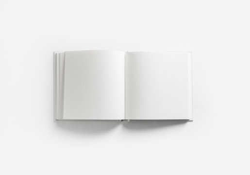 Opened blank square book on white paper background. Flat lay.