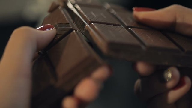 Woman breaks chocolate bar. Slow motion