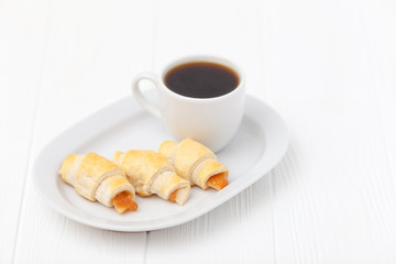 Freshly baked croissant, jam, cup of black coffee on white wooden background. Homemade cookie. Fresh pastries for breakfast. Delicious dessert. Closeup photography. Horizontal banner