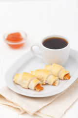 Freshly baked croissant, jam, cup of black coffee on white wooden background. Homemade cookie. Fresh pastries for breakfast. Delicious dessert. Closeup photography. Horizontal banner