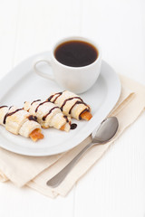 Freshly baked croissant, jam, cup of black coffee on white wooden background. Homemade cookie. Fresh pastries for breakfast. Delicious dessert. Closeup photography. Horizontal banner