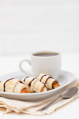 Freshly baked croissant, jam, cup of black coffee on white wooden background. Homemade cookie. Fresh pastries for breakfast. Delicious dessert. Closeup photography. Horizontal banner