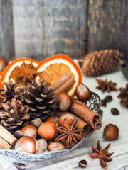 Winter ingredients nuts, cones, oranges, cinnamon star anise in a bowl. Rustic style