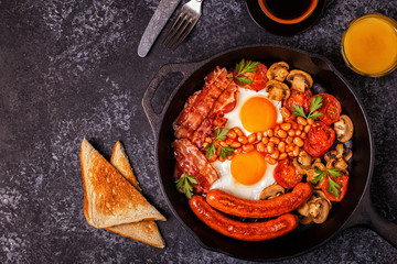 Traditional full English breakfast with fried eggs, sausages, beans, mushrooms, grilled tomatoes and bacon.