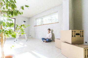 Schwangere Frau mit Tablet PC sitzt auf dem Boden auf der Baustelle im Haus