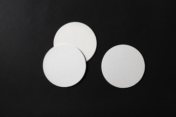 Three blank beer coasters on black paper background. Flat lay. © Veresovich