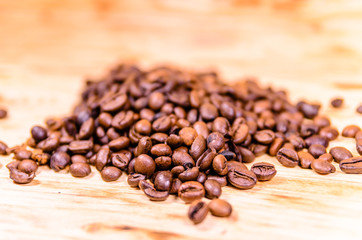 Pile of the roasted coffee beans on wooden table