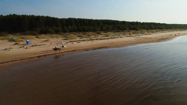 Two women riding horses on a beach