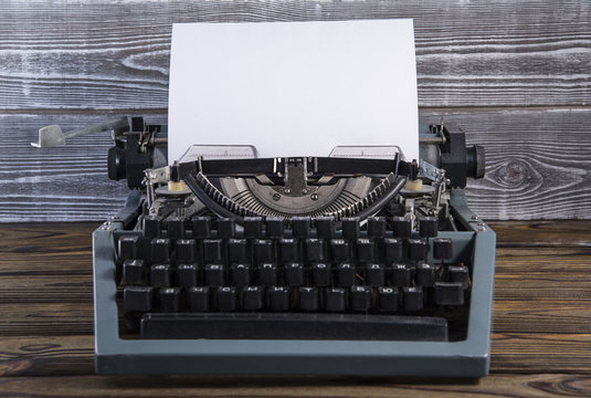 Vintage old typewriter with blank paper on a wooden table
