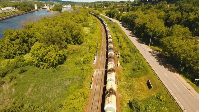 Freight train with cisterns and containers on the railway. Aerial view Container Freight Train, Locomotive in the countryside, Railway and highway. 4K, flying video, aerial footage.