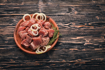 Raw uncooked meat sliced in cubes on wooden rustic background, top view.