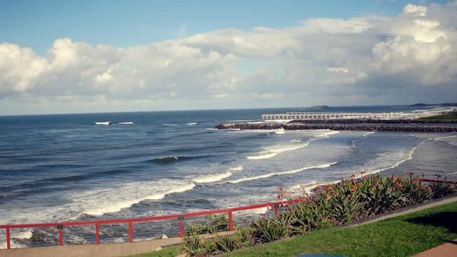 panning shot of ocean and a couple on bench