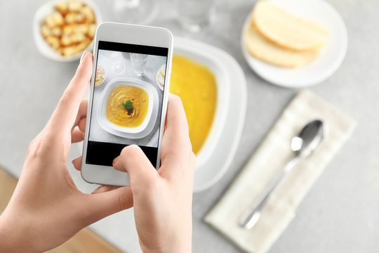 Blogger taking photo of lentils creme soup with cell phone